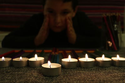 Boy looking at tea light candles on table
