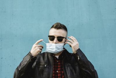 Portrait of man wearing sunglasses and mask against wall