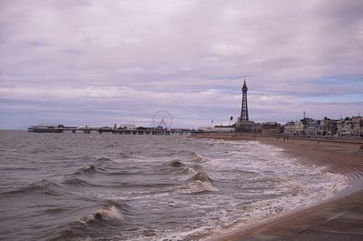 View of pier on beach against cloudy sky