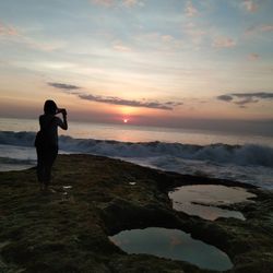 Man standing on beach against sky during sunset