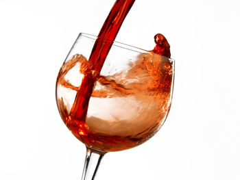 Close-up of wineglass on glass against white background