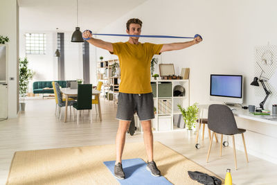 Young man standing on table at home
