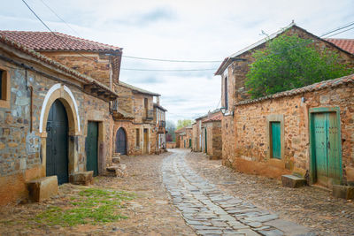 Alley amidst old buildings in city against sky