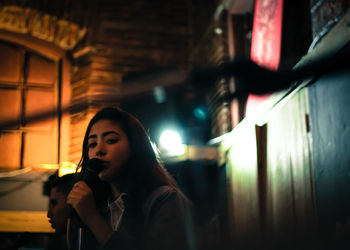 Portrait of woman singing on microphone at night