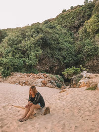 Full length of woman sitting on sand at beach