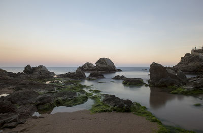 Rocks on sea against sky during sunset