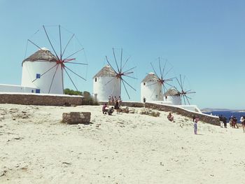 Traditional windmill on beach against clear blue sky