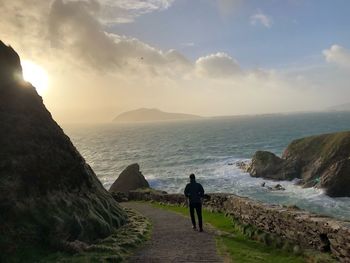 Rear view of man looking at sea against sky