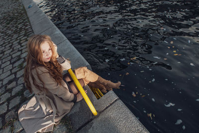High angle view of woman sitting by canal