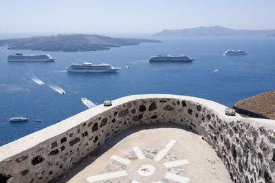 The volcanic caldera of the island of santorini is seen on a summer day with cruise ships.