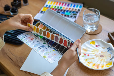 Cropped hand of woman using laptop on table