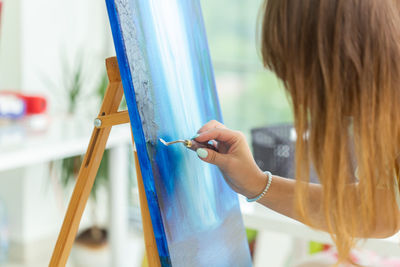 Woman painting on canvas at home