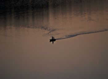 Silhouette person paragliding against sky during sunset