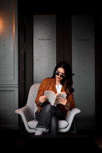 Full length of a young woman sitting on book