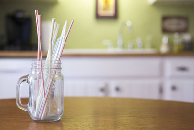 Close-up of drinking straws in mason jar on table