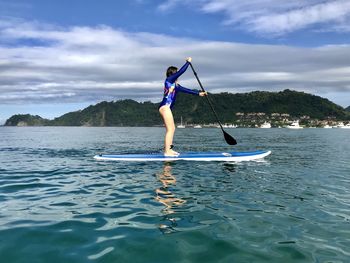 Man surfing in sea against sky