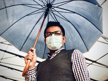 Man holding umbrella and wearing face mask in rain