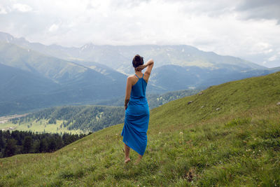 Rear view of woman standing on mountain against sky