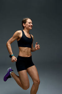 Young woman exercising against black background