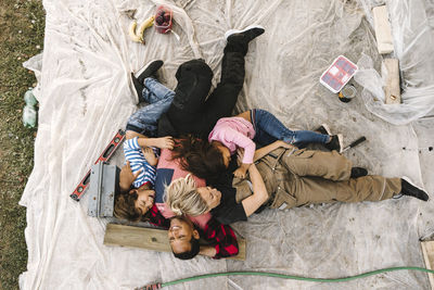 Smiling parents with children resting in yard after renovating during summer