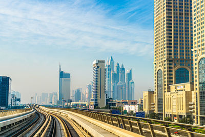 Panoramic view of railroad tracks amidst buildings in city against sky