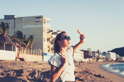 Young woman shading her eyes at beach at sunset