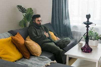 Young woman using laptop while sitting on sofa at home