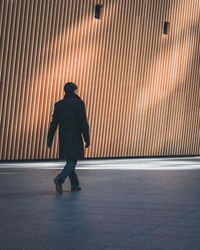 Rear view of man walking on street against building
