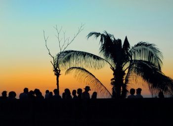 Silhouette people at beach against sky during sunset