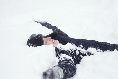 Woman lying on snow covered landscape