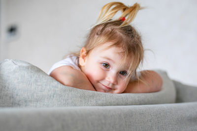 Portrait of cute girl lying on sofa at home