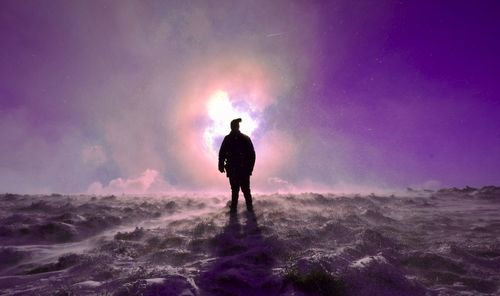 Rear view of man standing on field against sky