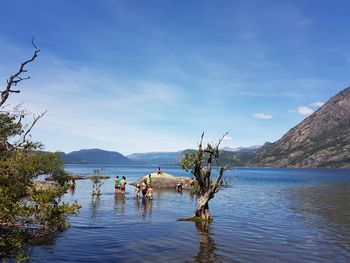 People in lake against sky