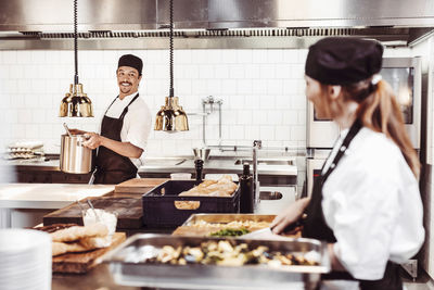 Smiling chefs looking at each other in commercial kitchen