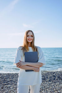 Portrait of young woman standing at beach