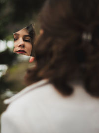 Rear view of woman holding piece of mirror