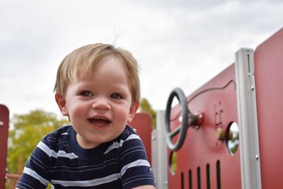 Cute smiling baby boy against cloudy sky