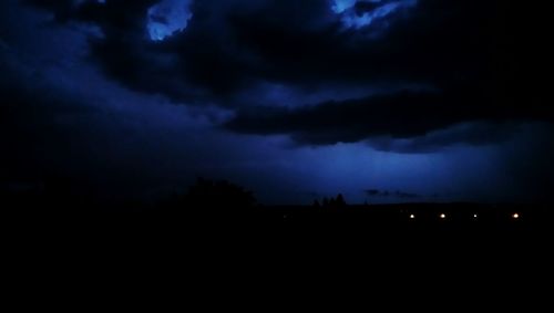 Silhouette landscape against cloudy sky at night