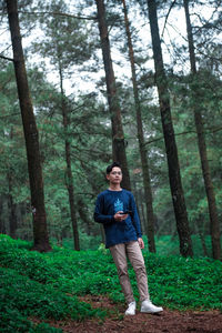 Full length portrait of young man standing at forest