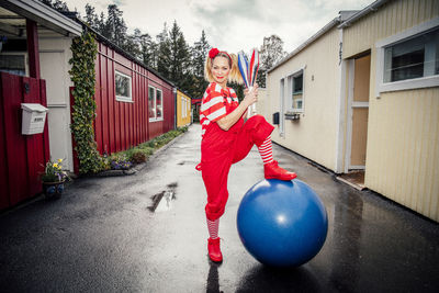 Portrait of smiling woman standing by fitness ball on road