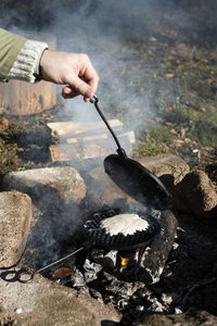 Mature man preparing waffles at bonfire