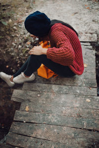 Young woman sitting on a small wooden bridge in the forest