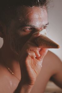 Close-up of man applying ice cream on face