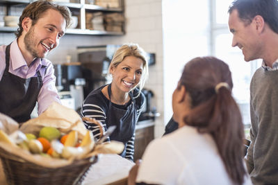 Male and female owner attending customers at counter in restaurant