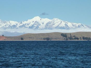 Scenic view of sea and snowcapped mountains against sky