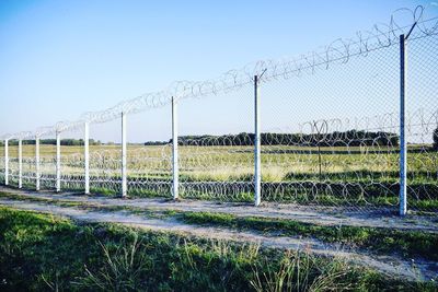 Fence on grassy field against clear sky