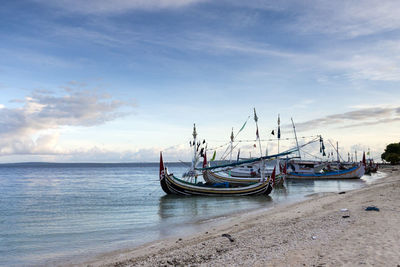 Sailboats moored on sea against sky