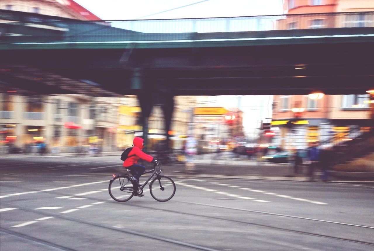 transportation, mode of transport, land vehicle, bicycle, street, car, city, architecture, road, building exterior, built structure, on the move, blurred motion, city life, motion, travel, riding, city street