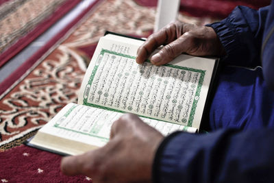Midsection of man reading book on paper