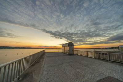 Bridge over sea against sky during sunset